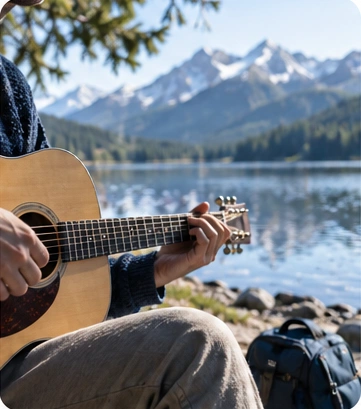 Playing an acoustic guitar beside a mountain lake.